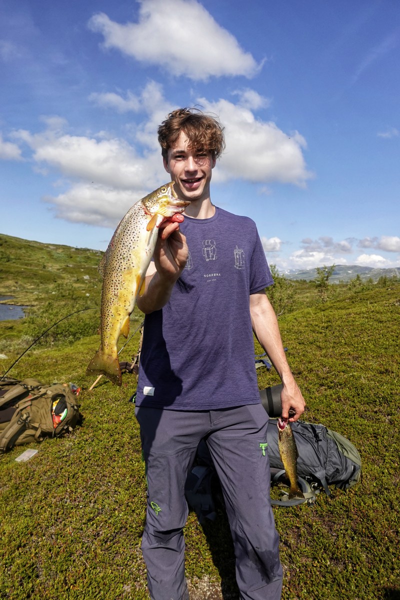 Ung mann som holder en 700 gram ørret i høyre hånden og viser den frem